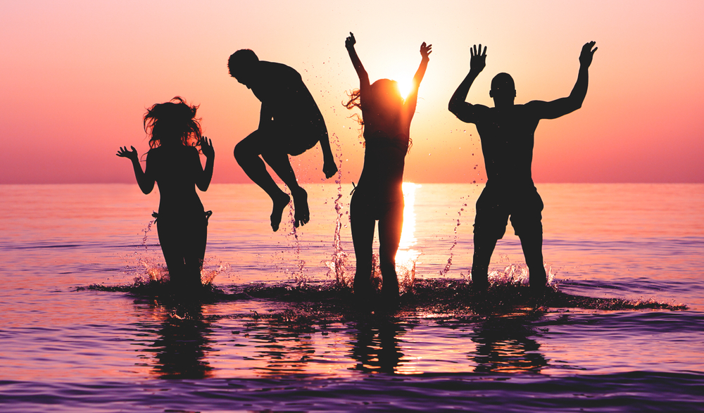 friends jumping in water on tropical beach at sunset Silhouette