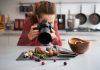 4 Food Photography Lenses You Need in Your Kit food photographer in a kitchen with fall fruits and vegetables