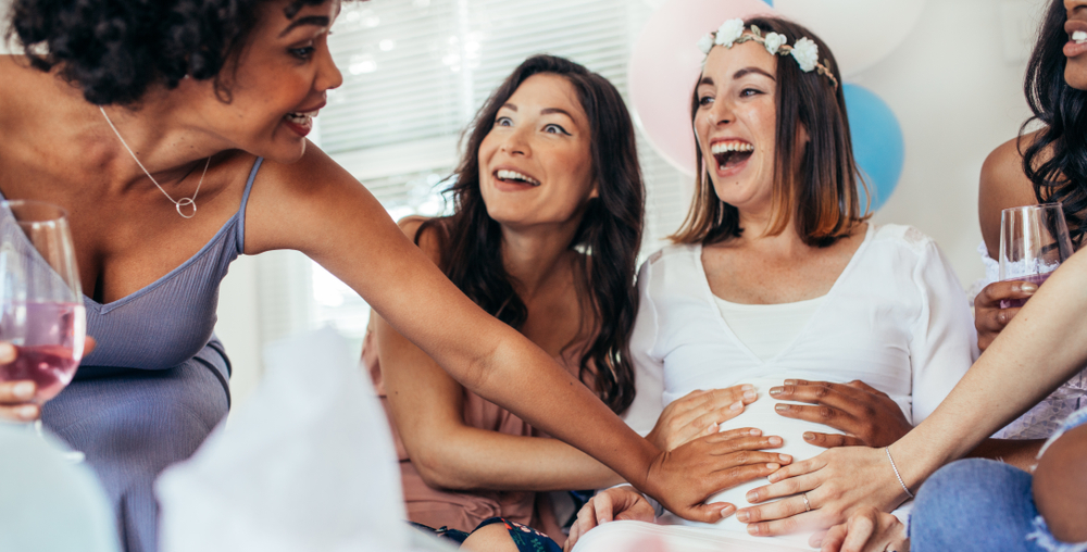 female friends touching pregnant woman's belly at baby shower