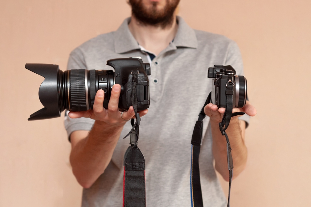 Man holding two cameras