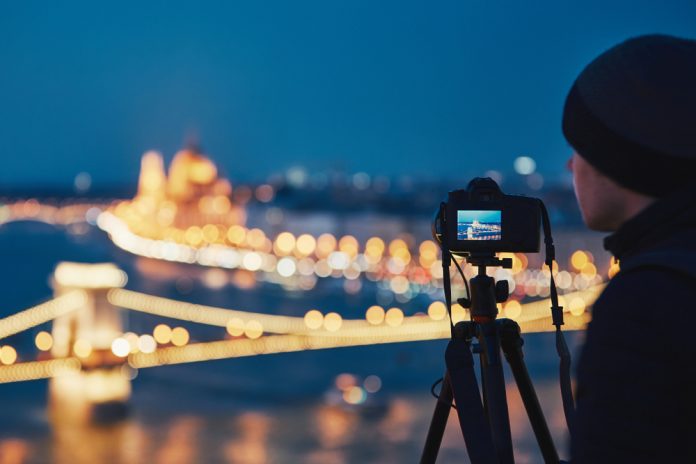 Photographer with tripod taking photos at night