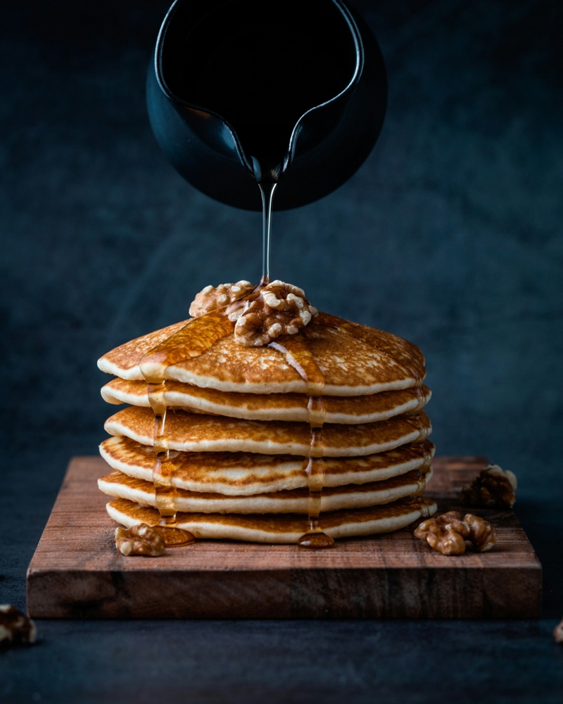 syrup being poured on pancakes