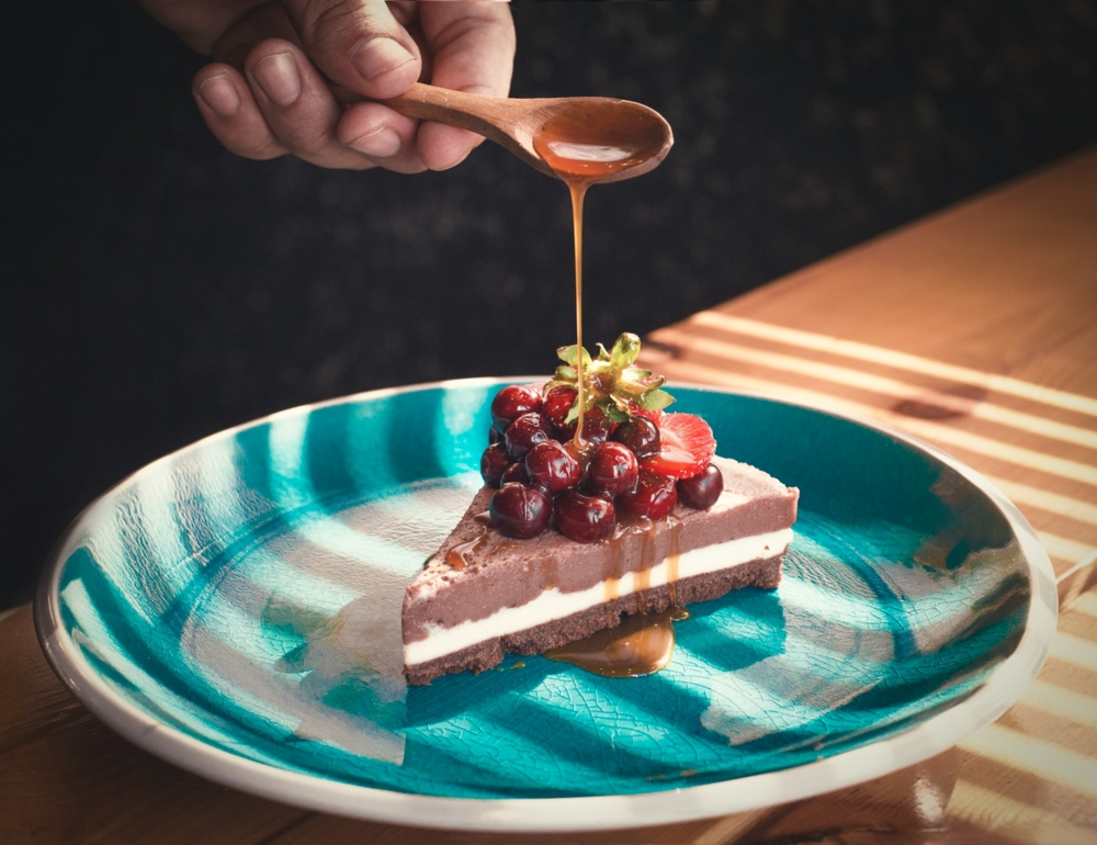 a person using a spoon to pour caramel on a cake