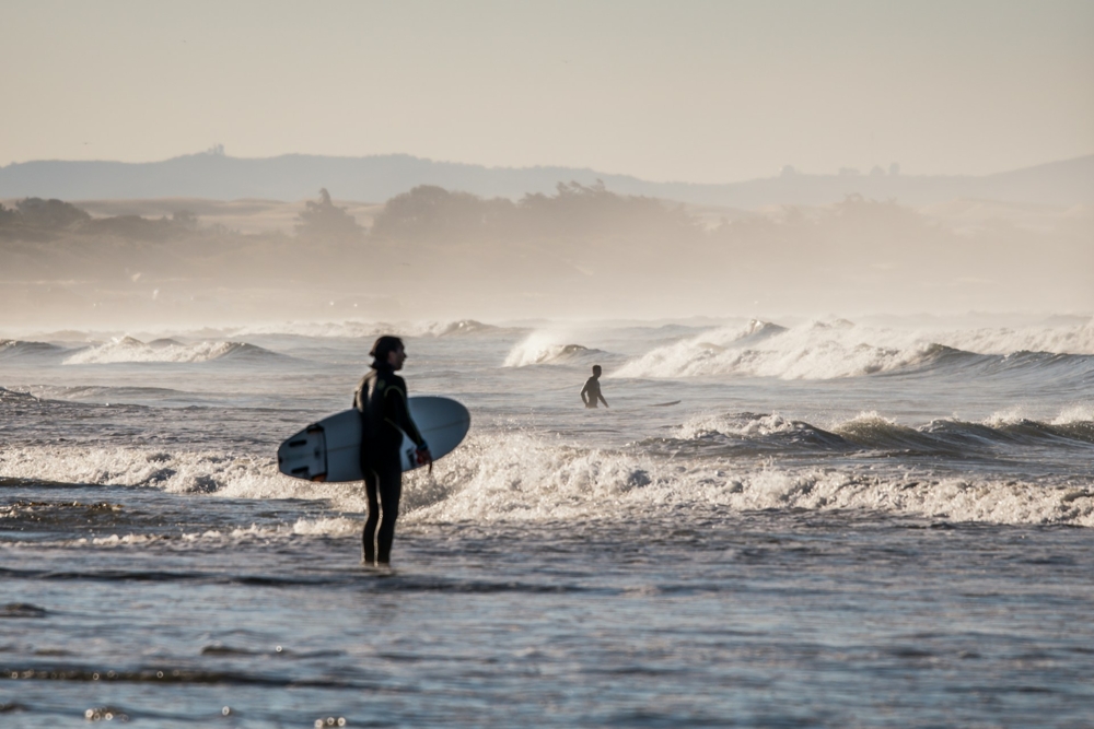 person holding white surfboard standing in the ocean