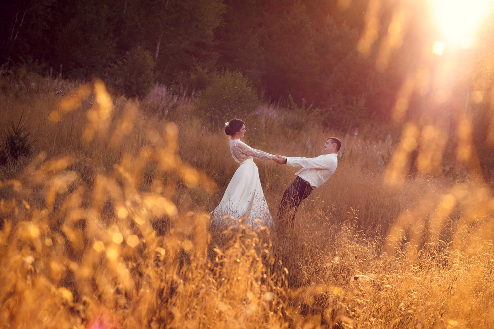 Bride and groom in field at golden hour