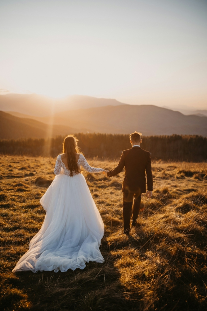 Groom leading bride through a field