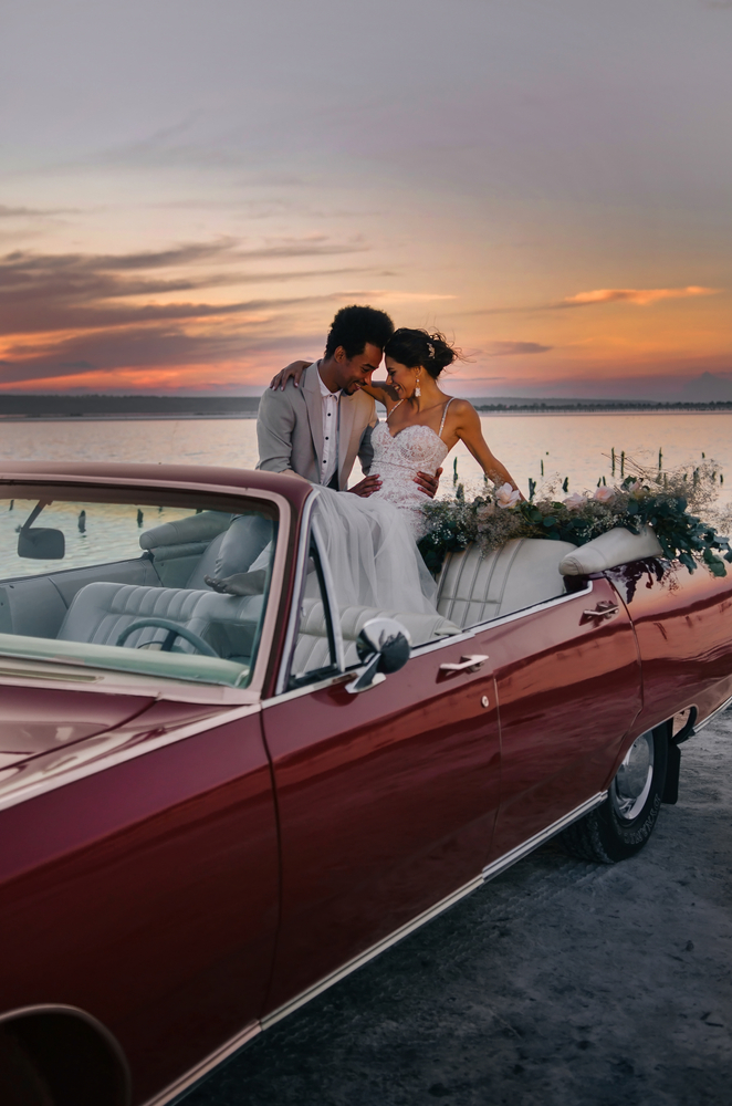 Bride and groom sitting on a convertible
