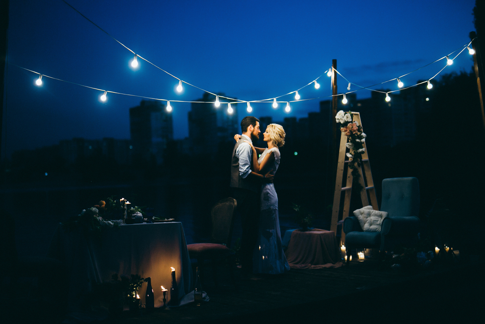 Couple dancing at night under strings of lights