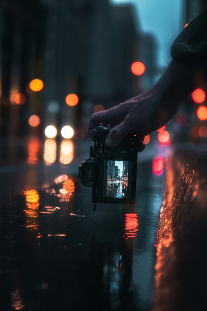 person holding camera taking photo of city lights