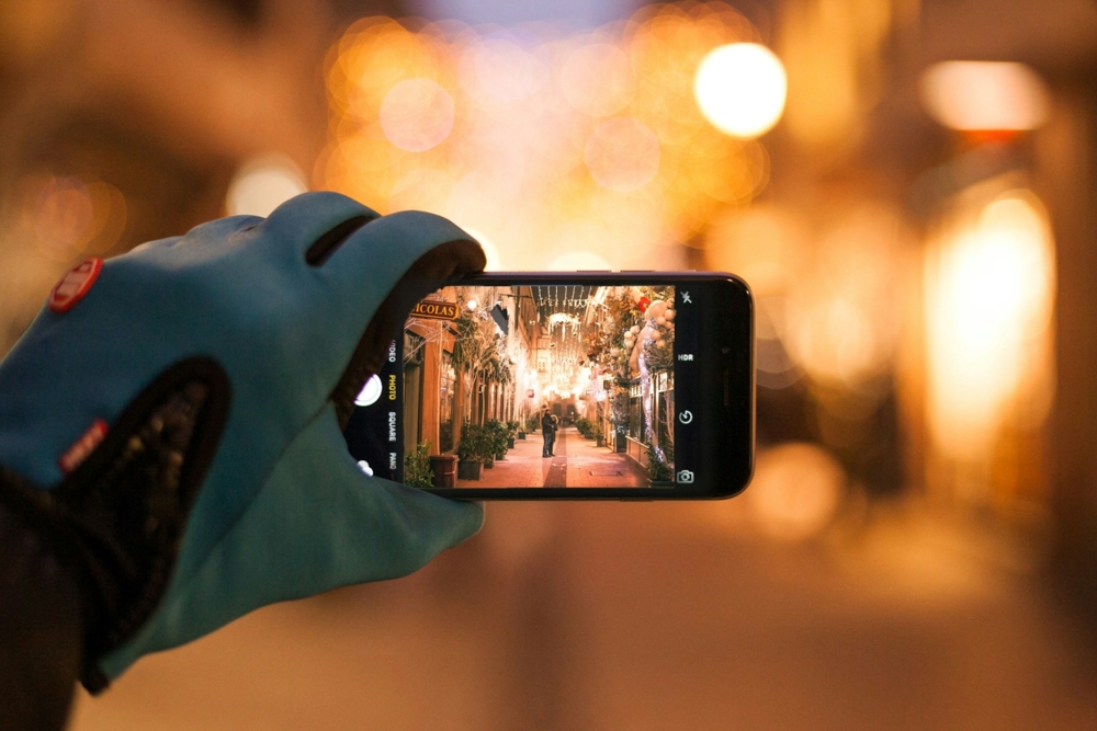 Close up of a gloved hand taking a photo with a phone