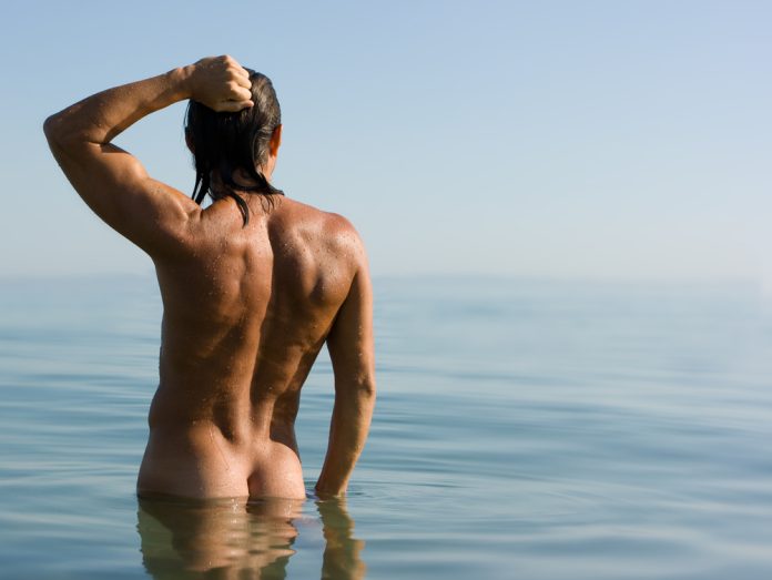 young man posing nude in the water
