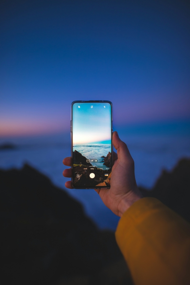 Person holding a smartphone taking a photo of the ocean