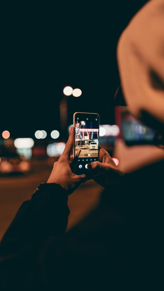 a person taking a picture with a cell phone at night