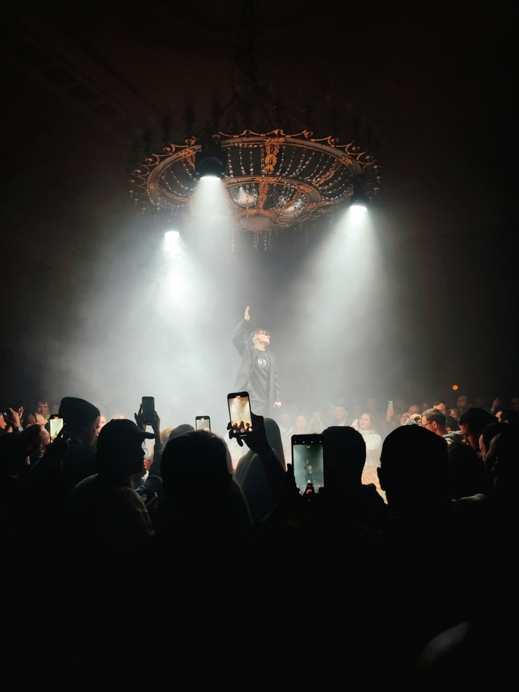 People using smartphones to take photos of a singer on stage
