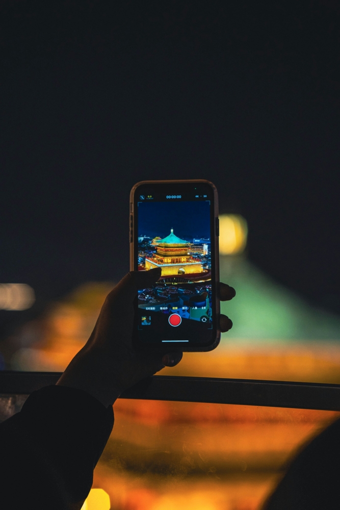 A person taking a picture of a city at night