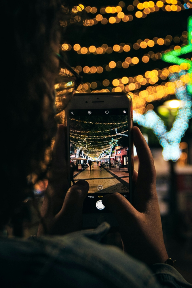 a person taking a picture of a decorated street night