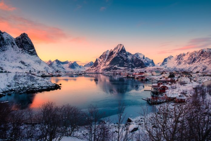 sunrise sky over Reine town with fishing village and snow covered mountain