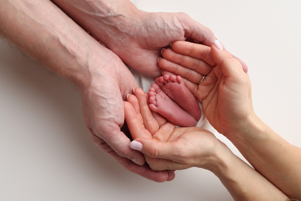 palms of the mother and father hold the feet of a newborn baby 
