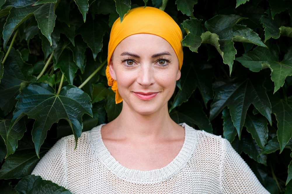 Woman in a yellow headscarf standing in front of a bush