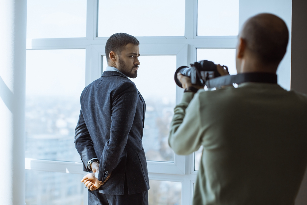 photographer captures a stylish businessman posing in front of large office windows