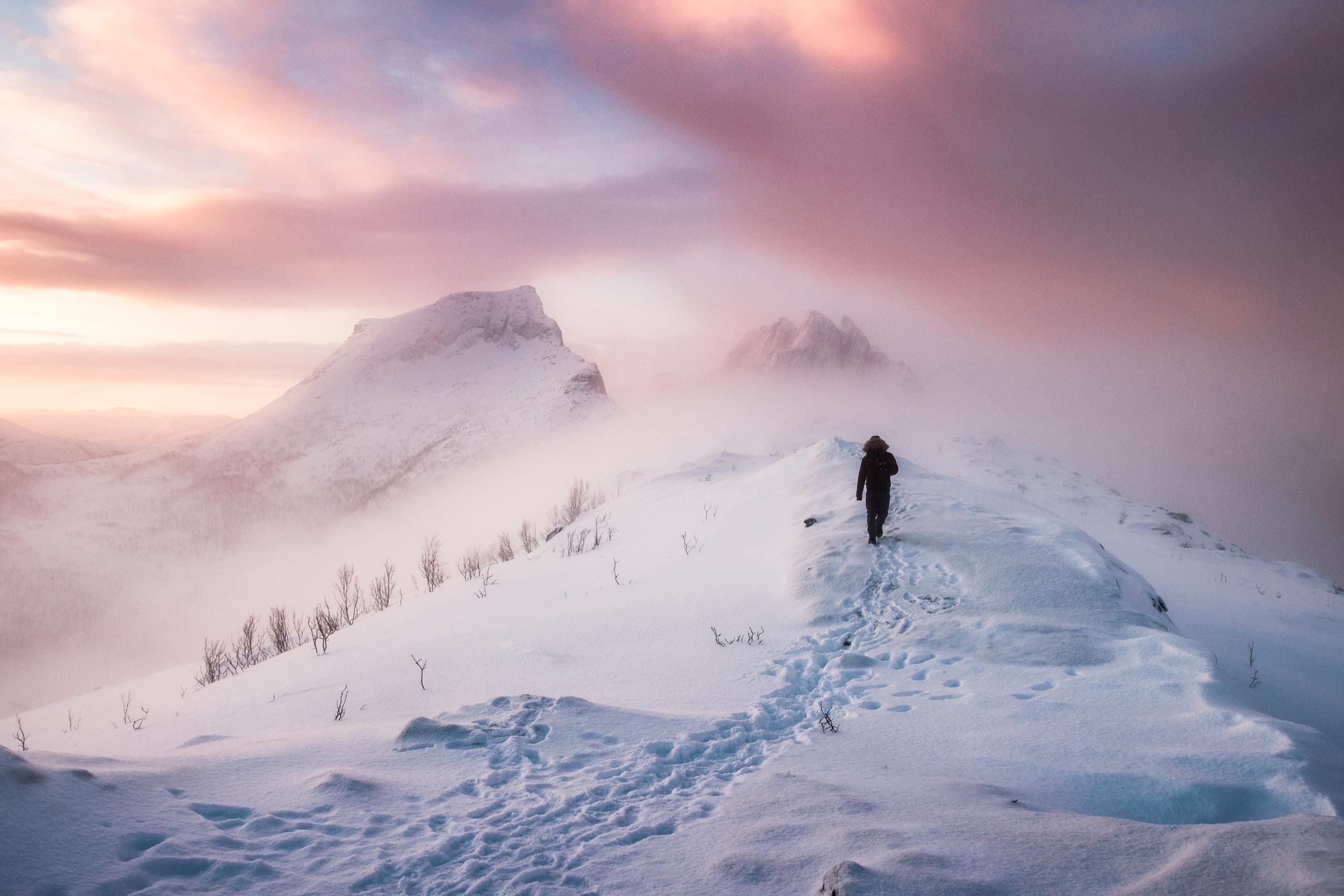 man walking on a mountain ridge in a blizzard of snow