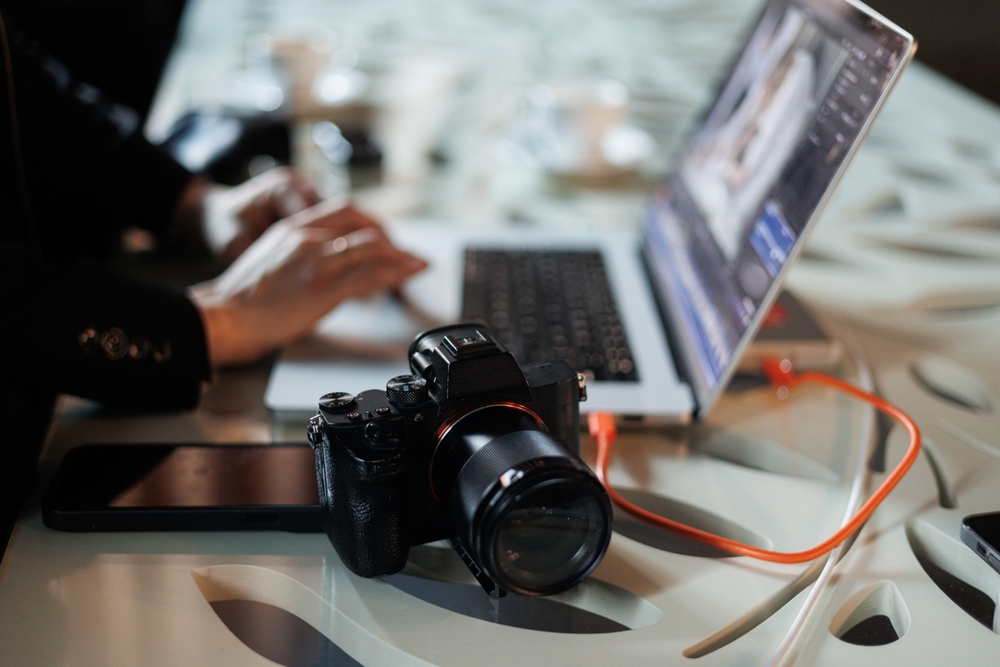 photographer working on a laptop with their camera nearby