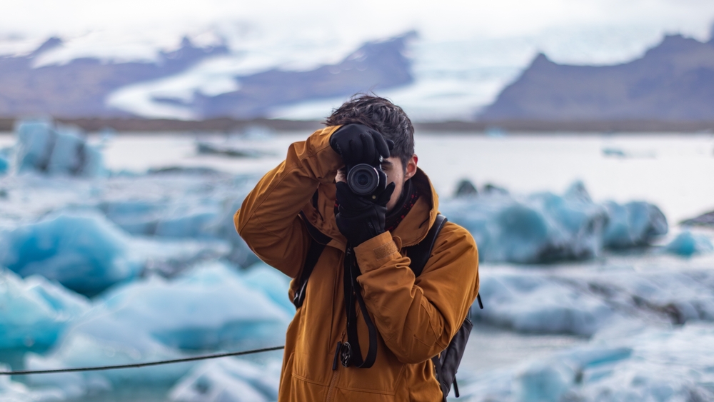  photographer taking a picture with a glacier in the background in Iceland
