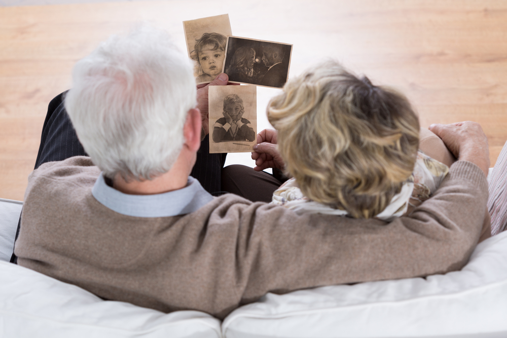 senior couple sitting on the sofa and looking at old photos