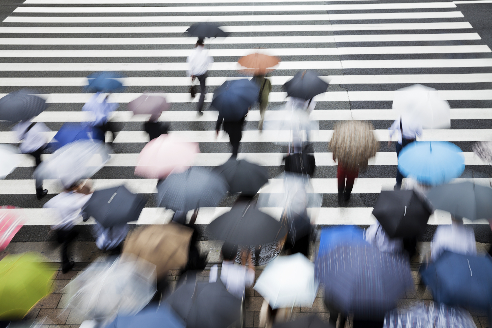 People holding umbrellas walking across the street Motion Blur