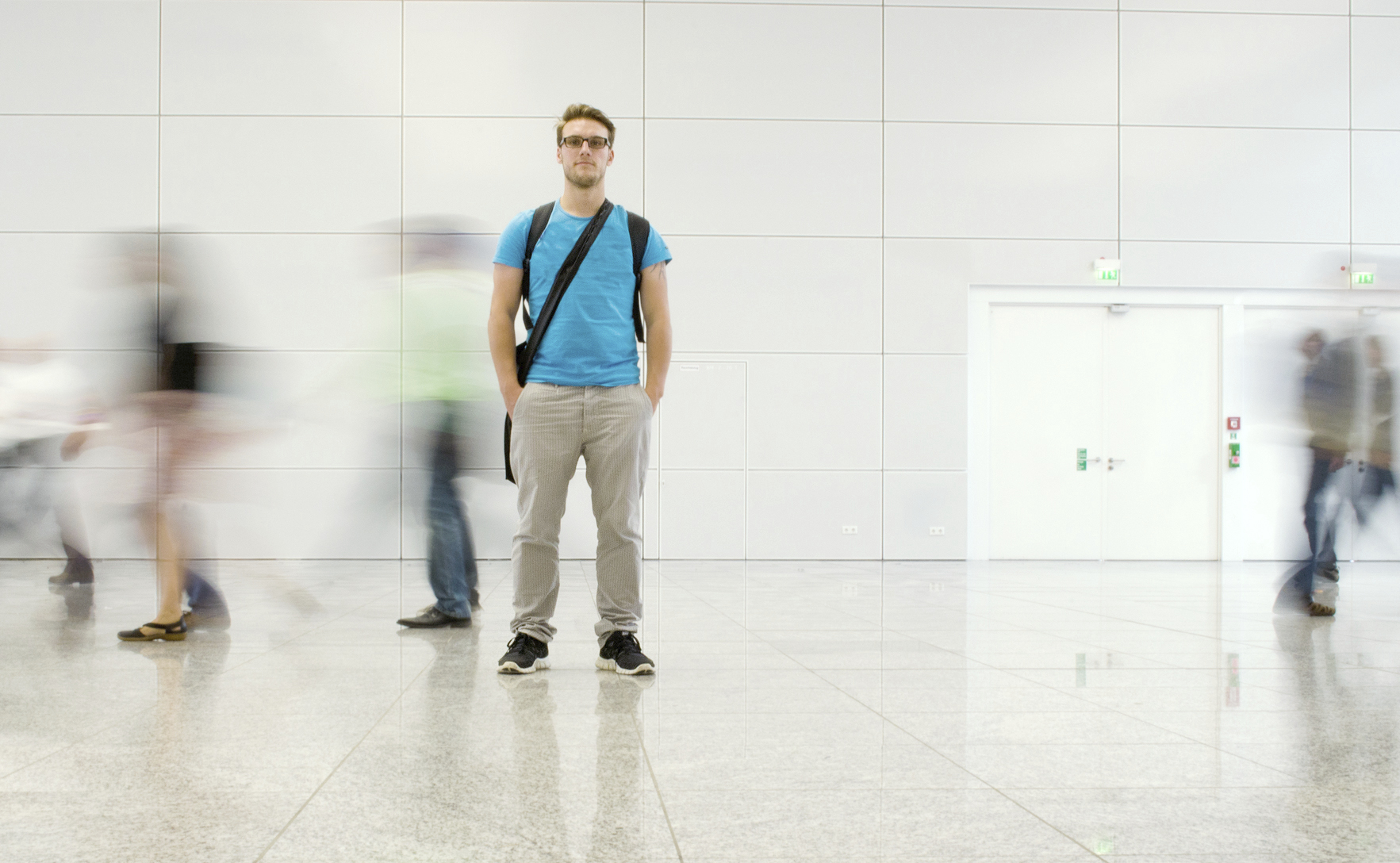 Man standing still while people are walking around him motion blur