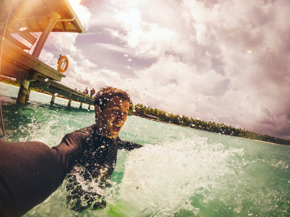 man using gopro to take a selfie in the ocean