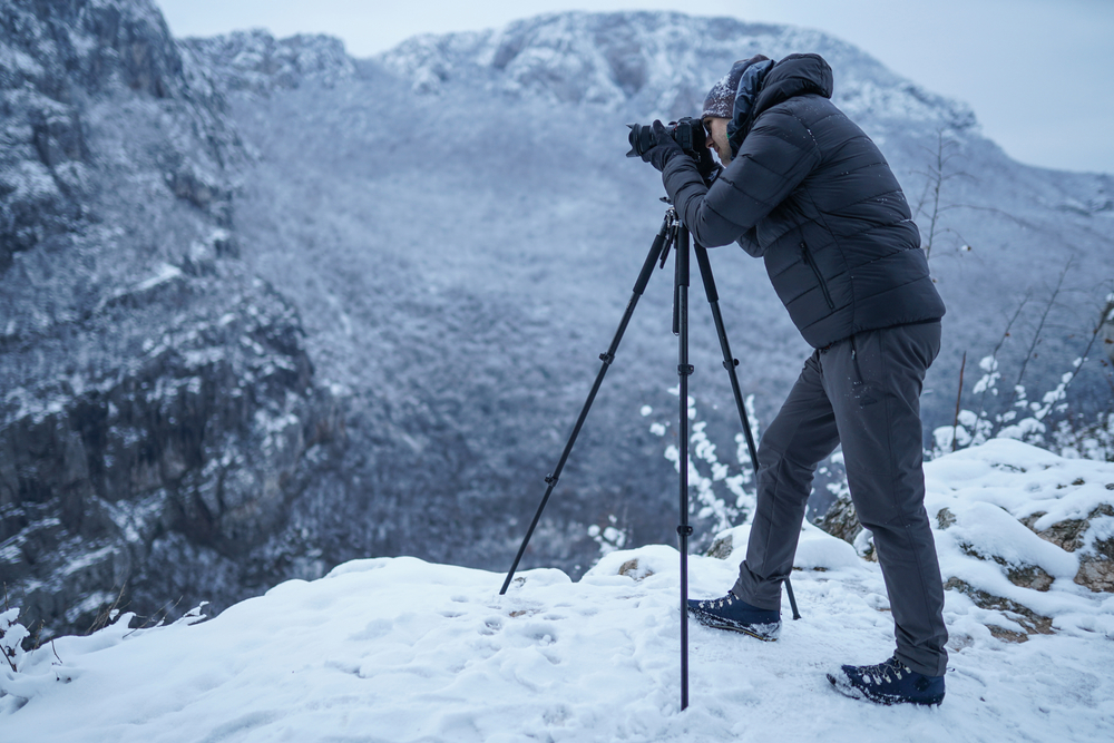 male photographer with camera and tripod in winter
