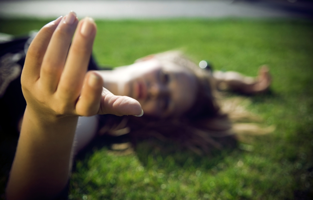 woman laying on the ground reaching out her hand, shallow depth of field