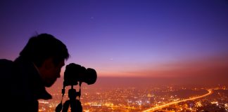 photographer with tripod photographing a city at night