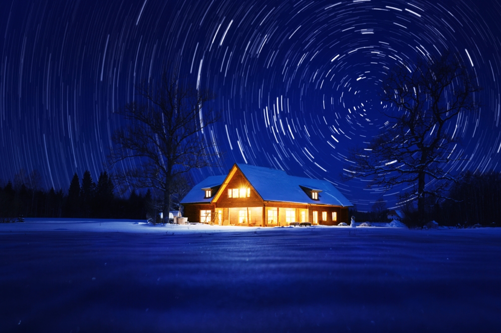Star trails over a cabin in winter