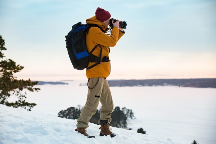 photographer with backpack taking a photo in winter