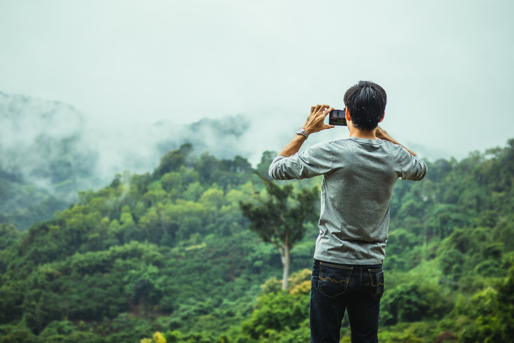man taking smartphone photo in the rain