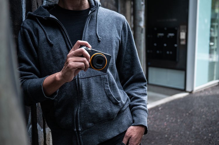 Man holding a Ricoh GR III with an orange ring
