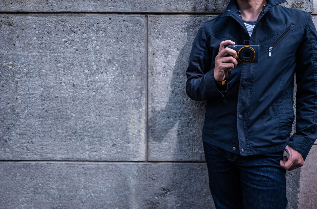 Man holding a Ricoh GR III with an orange ring 2