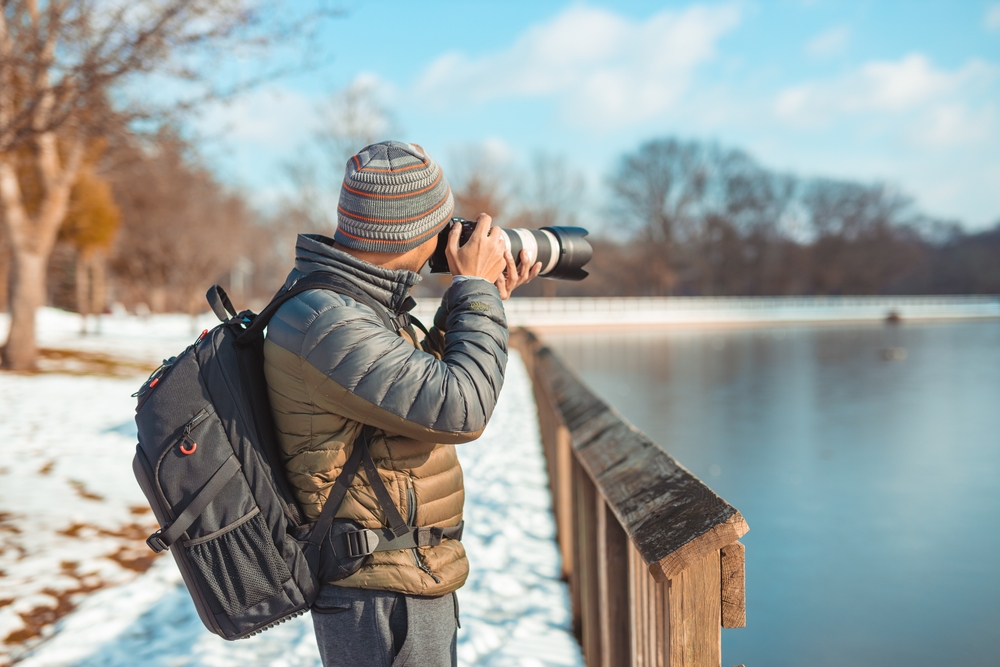 photographer with camera and telephoto lens in winter
