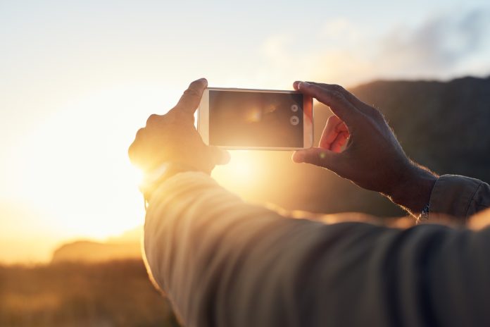 Person taking photos of the sunset with a cell phone